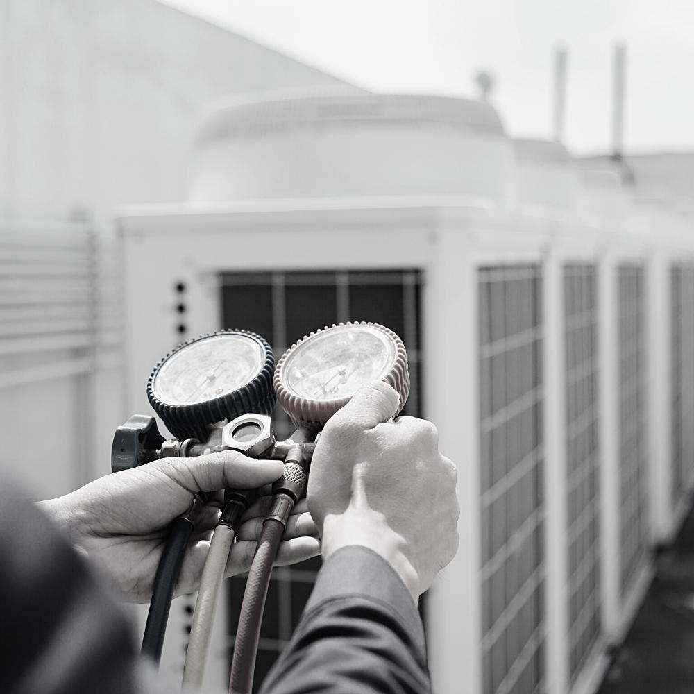 Air Conditioner Installation 1 A person performing an air conditioner installation holds two units in a black and white photo.