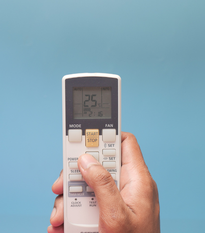 a person holding an AC remote control in their hand.